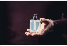 زجاجات عطور رجالية فاخرة مرتبة على سطح خشبي داكن مع إضاءة دافئة